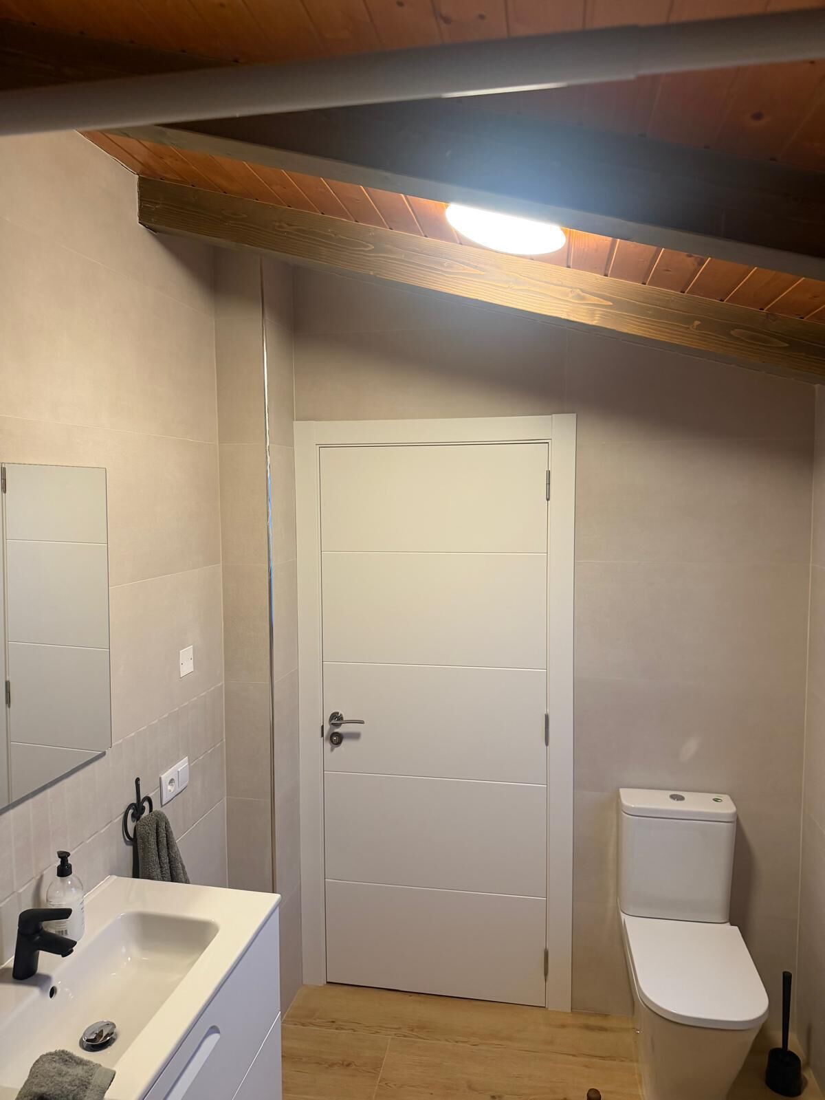 Un baño con un lavamanos blanco, un inodoro y una puerta.