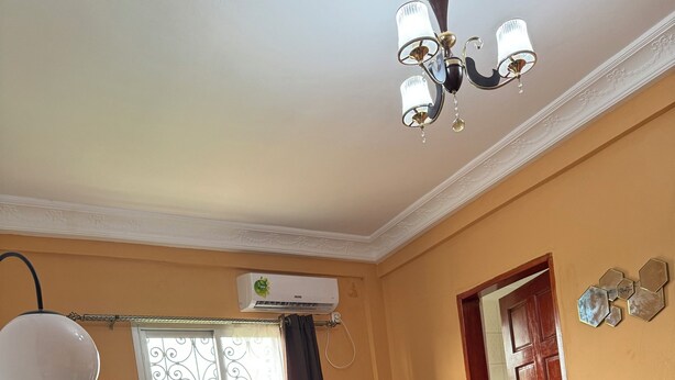 A living room with a sofa, a dining table, and a chandelier. - Elegant 1 BDR Apt | in Comfort & Style (Yaoundé)
