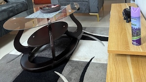 A living room with a sofa, a glass coffee table, a wooden side table, and a decorative lamp. - Elegant 1 BDR Apt | in Comfort & Style (Yaoundé)