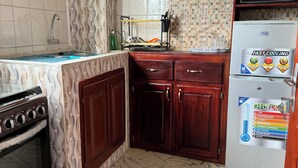 A kitchen with a tiled backsplash, wooden cabinets, a stainless steel refrigerator, and a built-in oven. - Elegant 1 BDR Apt | in Comfort & Style (Yaoundé)