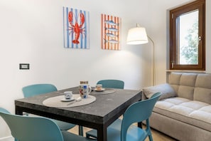 A dining area with a table, chairs, and artwork on the wall.