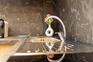 Une cuisine avec un dosseret en marbre, un évier en acier inoxydable et un vase rempli de fleurs.