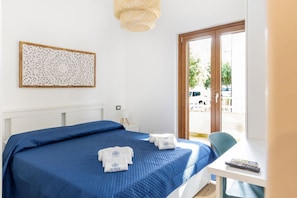 Une chambre d’hôtel avec un lit, un bureau et une chaise, une fenêtre et une porte.