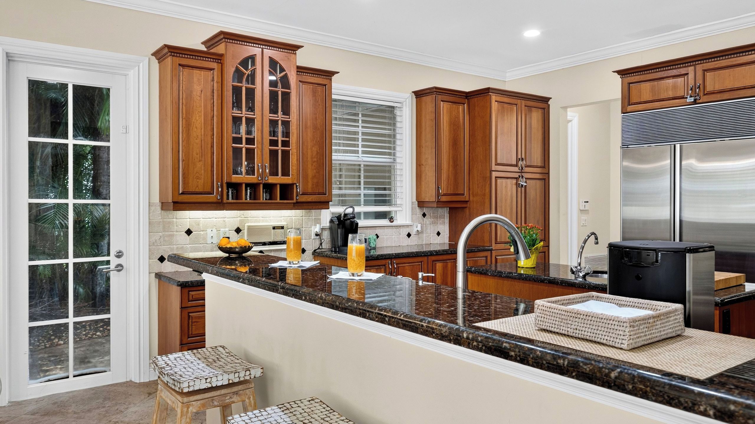 Una cocina con armarios de madera, un refrigerador de acero inoxidable y una encimera de granito.
