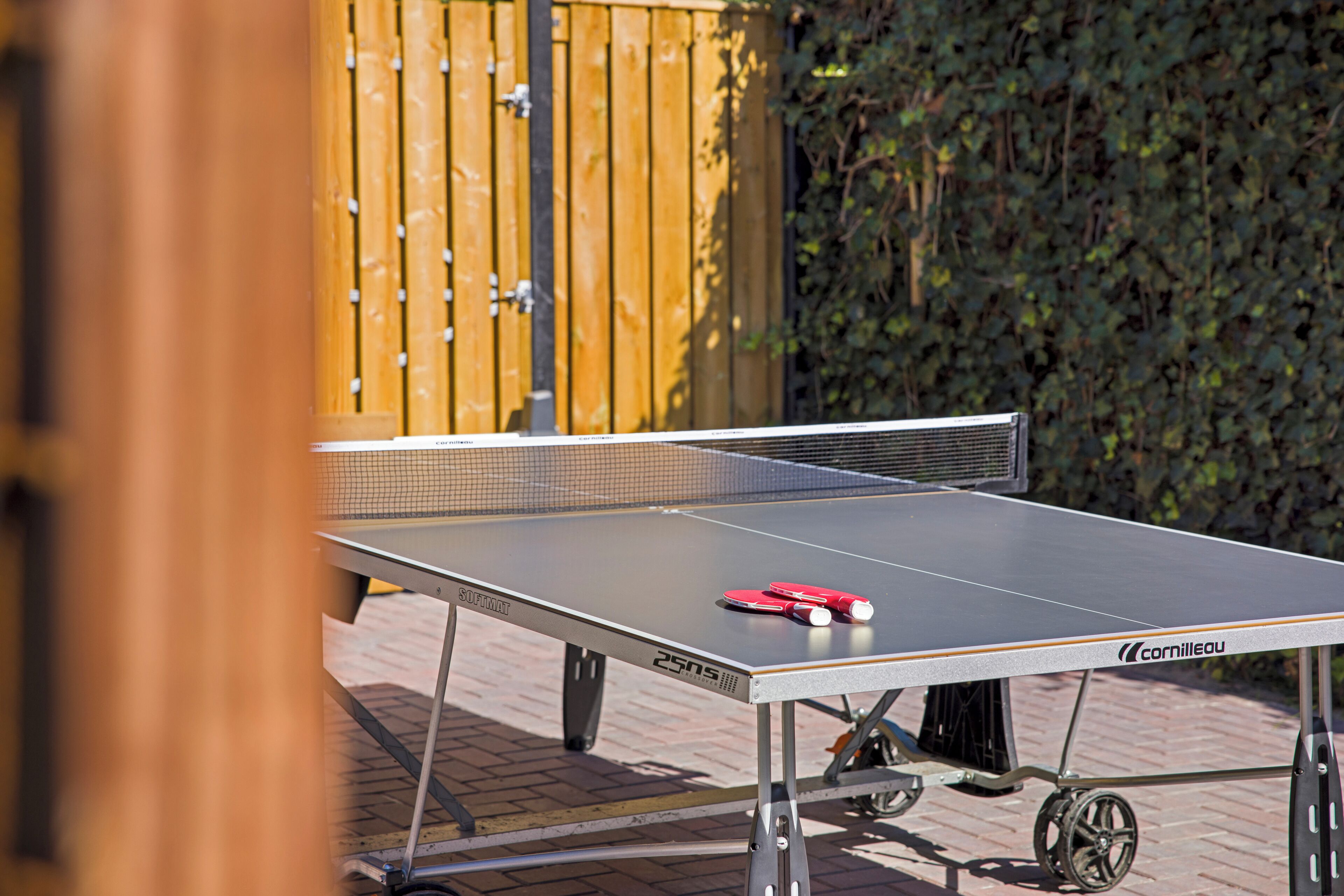 Une table de ping-pong portable, avec un filet, installée à l’extérieur sur une surface pavée.