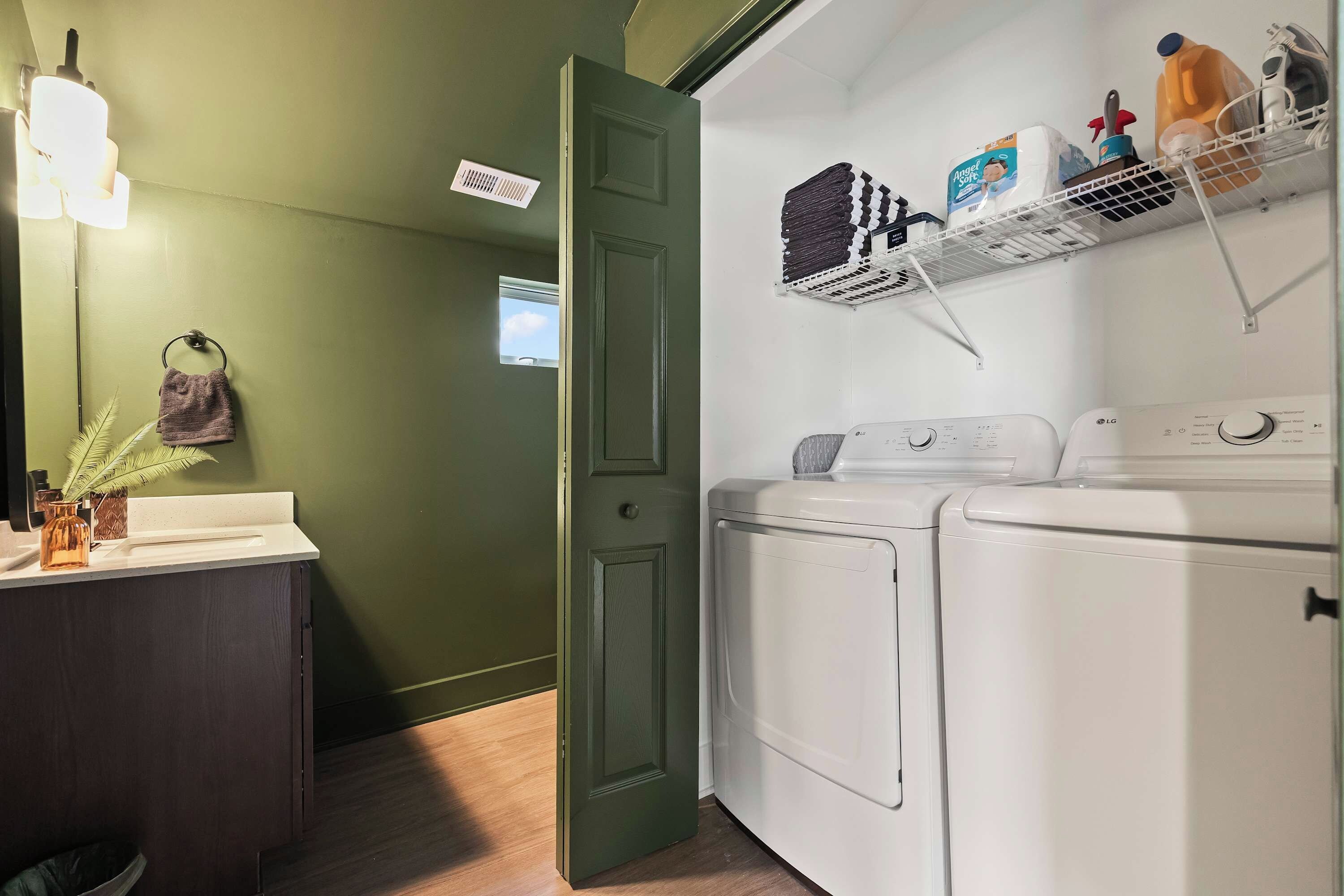 A laundry area with a washing machine, dryer, and shelves with laundry supplies.