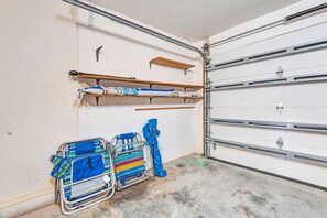 Eine Garage mit weißer Tür, Metallregalen und zwei Rollstühlen.