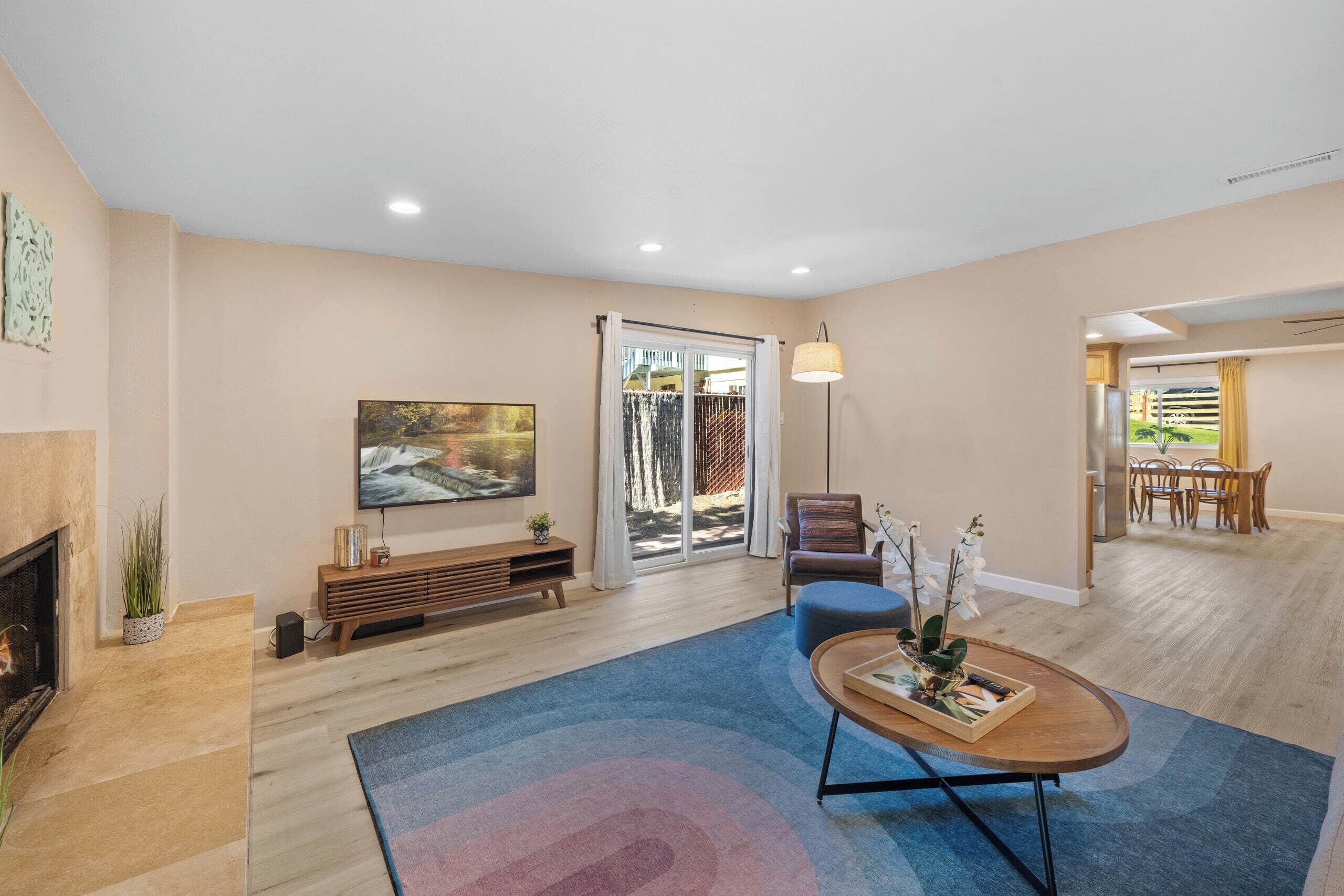 A spacious living room with a fireplace, a large painting, a sofa, and a dining area with a table and chairs.