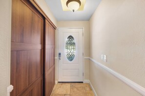 A hallway with a wooden door, a glass door with a decorative design, and a ceiling light fixture. - Spacious and Serene North Park Home (San Diego)