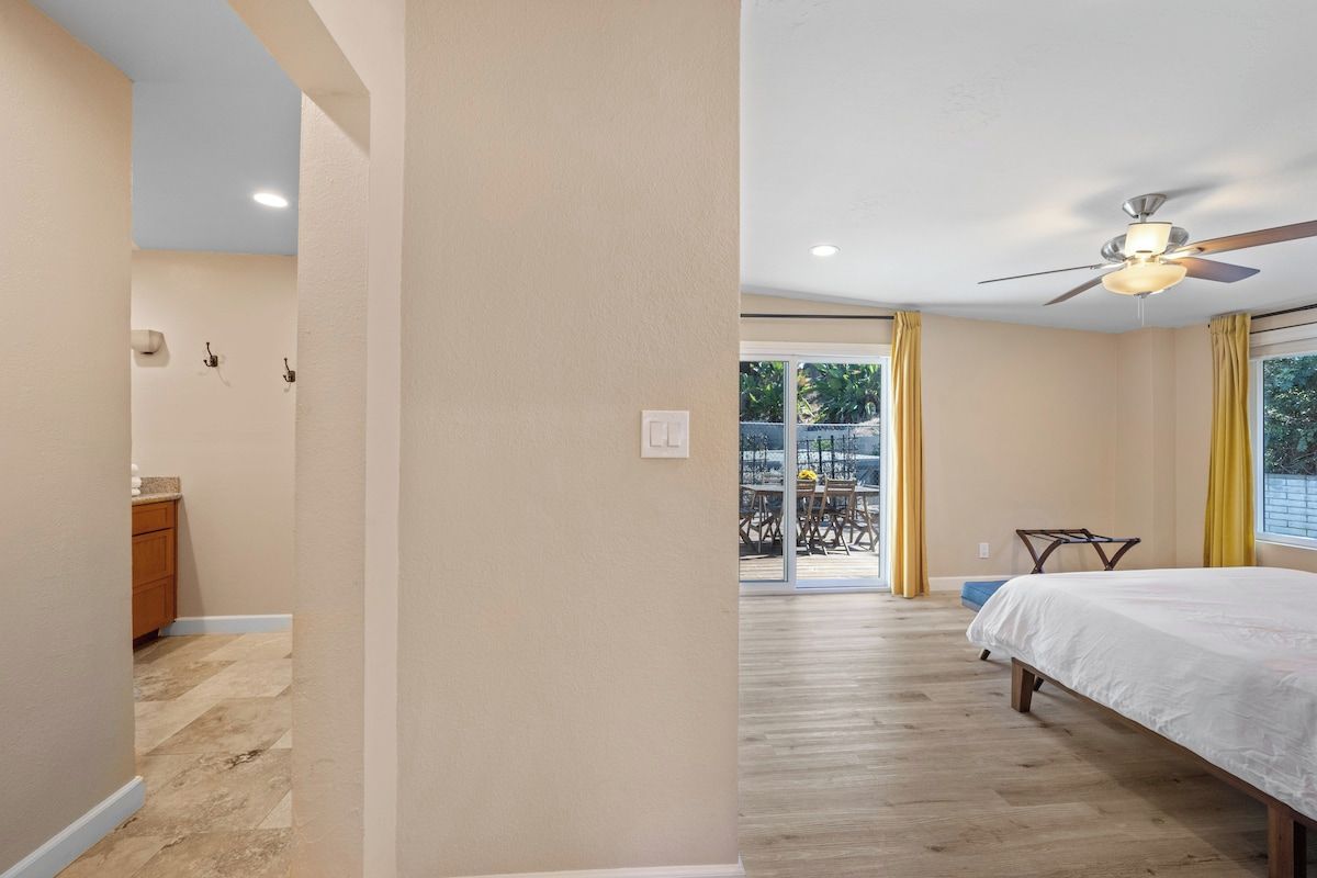 Une chambre à coucher avec un lit, un ventilateur de plafond et une vue sur un patio extérieur.