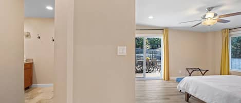 Une chambre à coucher avec un lit, un ventilateur de plafond et une vue sur un patio extérieur.