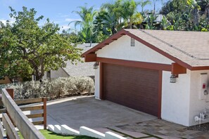 A small building with a garage door, surrounded by a wooden fence and various plants. - Spacious and Serene North Park Home (San Diego)