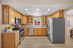 A kitchen with wooden cabinets, stainless steel appliances, and a central island with a sink. - Spacious and Serene North Park Home (San Diego)