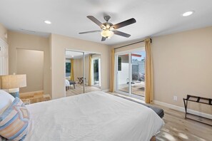 A bedroom with a bed, a ceiling fan, a sliding glass door to a balcony, and a view of the outside. - Spacious and Serene North Park Home (San Diego)