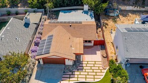 Una propiedad residencial con techo inclinado, paneles solares, piscina y césped bien cuidado.