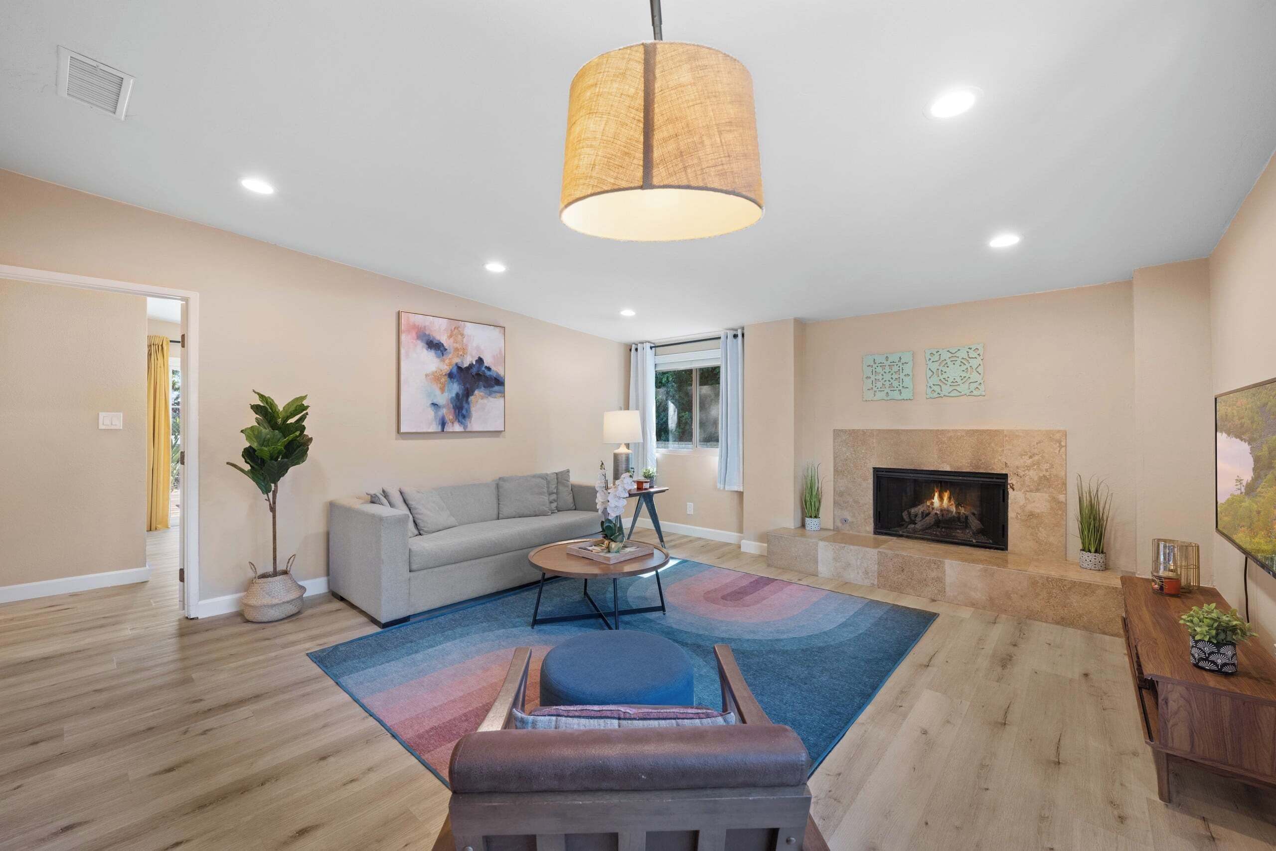 A living room with a sofa, coffee table, rug, and a fireplace.