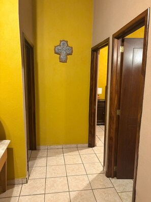 Um corredor com paredes amarelas, moldura de porta de madeira e chão de azulejos.