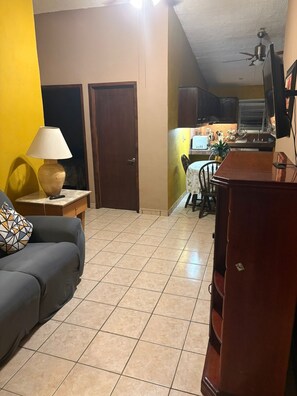 A living room with a sofa, a lamp, and a dining area with a table and chairs. - Family-friendly apartment with AC, hot water, and Wi-Fi, near downtown and Costco (Puerto Vallarta)