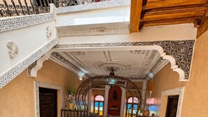 A multi-level interior with ornate railings, a central seating area, and a patterned floor. - Charming 5-Bedroom Mini Riad with Patio, Gym and Inspiring Workspace (Marrakech)