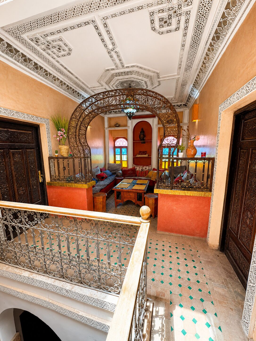 A traditional interior with ornate metal railings, a central seating area with cushions, and a patterned floor.