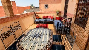 An outdoor patio with a round table and chairs, a sofa, and a guitar. - Charming 5-Bedroom Mini Riad with Patio, Gym and Inspiring Workspace (Marrakech)