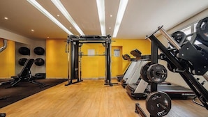 Une salle de sport équipée de matériel d’exercice, d’une barre de traction et d’un tapis de course.