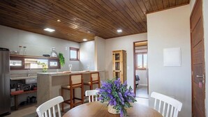 A kitchen with modern appliances, a dining area with a wooden table and chairs, and a wooden ceiling. - Apt. w/ Pool & View in Barra Grande Ldi0008 (Maraú)