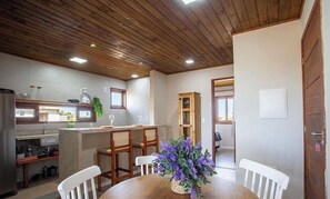 A kitchen with modern appliances, a dining area with a wooden table and chairs, and a wooden ceiling. - Apt. w/ Pool & View in Barra Grande Ldi0008 (Maraú)