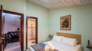 A hotel room with a bed, a shower, a chair, and a painting on the wall. - Apt. in Condo. w/ Pool & BBQ Cvc0010 (Camaçari)