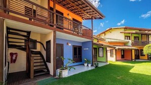 A multi-story building with a staircase leading to a balcony, a well-maintained lawn, and a clear sky. - Apt. in Condo. w/ Pool & BBQ Cvc0010 (Camaçari)