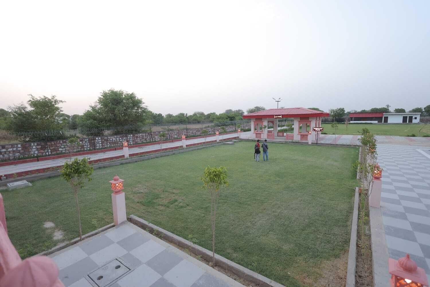 Un parco con un gazebo, un pavimento a scacchi e un muro in pietra.