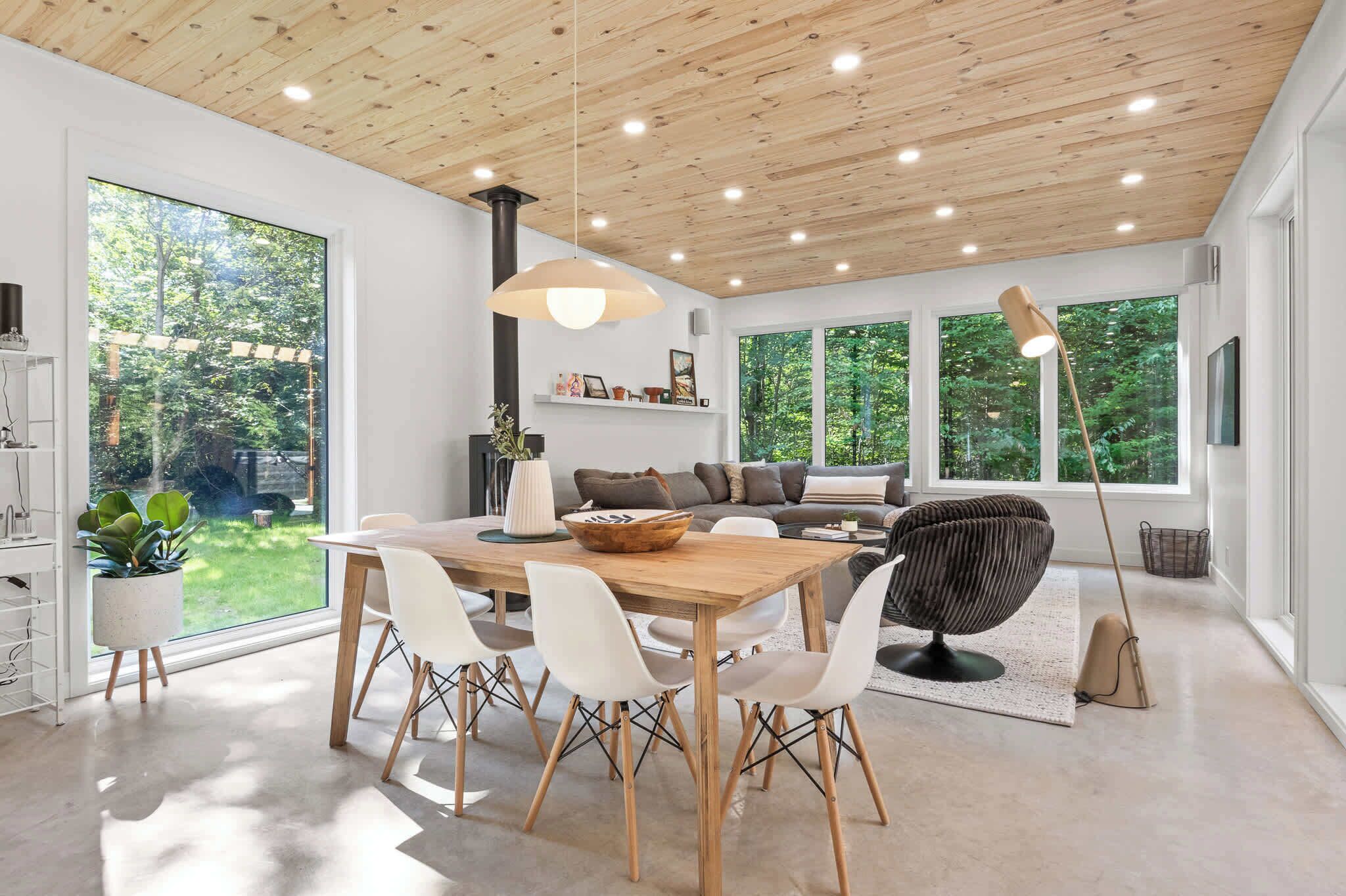 A modern interior with a dining area, seating, and large windows.