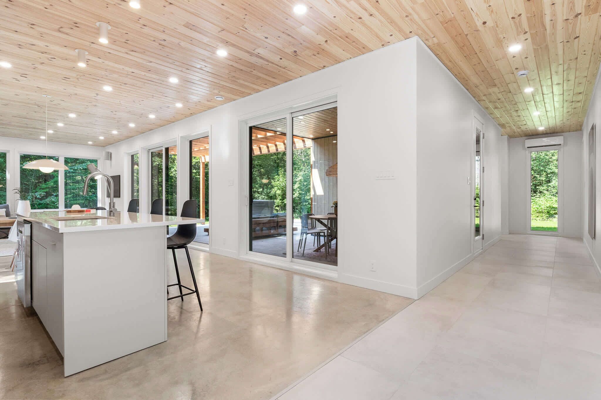 A modern kitchen with a central island, large windows, and a view of the outdoors.