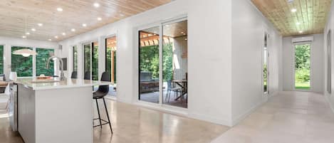 A modern kitchen with a central island, large windows, and a view of the outdoors.