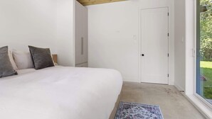 A bedroom with a large bed, a wardrobe, and a door leading to a balcony. - Slo | Luxury, Spa & 2 Saunas Memphremagog lake (Stanstead)