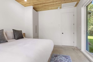 A bedroom with a large bed, a wardrobe, and a door leading to a balcony. - Slo | Luxury, Spa & 2 Saunas Memphremagog lake (Stanstead)