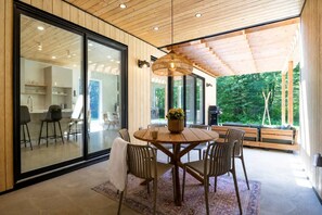 A modern interior with a round wooden table, chairs, and a hanging light fixture. - Slo | Luxury, Spa & 2 Saunas Memphremagog lake (Stanstead)