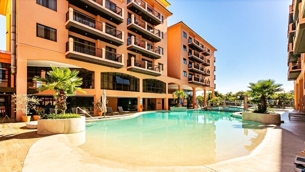 A hotel with a swimming pool, outdoor seating, and a multi-story building with balconies. - Studio With Balcony in a Cond. With Pool Jbv0432 (Florianópolis)