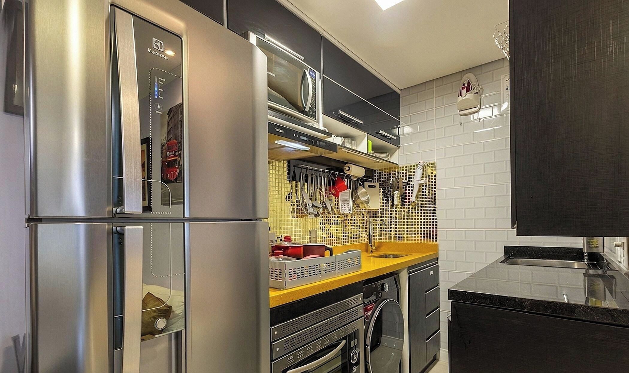 Una cocina compacta con un refrigerador de acero inoxidable, un microondas y un lavamanos.