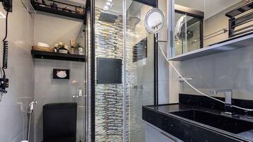 Un baño moderno con cabina de ducha de vidrio, encimera negra y pared decorativa con diseño de mosaico.