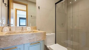 Ein modernes Badezimmer mit Marmorplatte, Toilette und einer Duschkabine aus Glas.