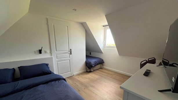 Een slaapkamer met een bed, een bureau en een raam.