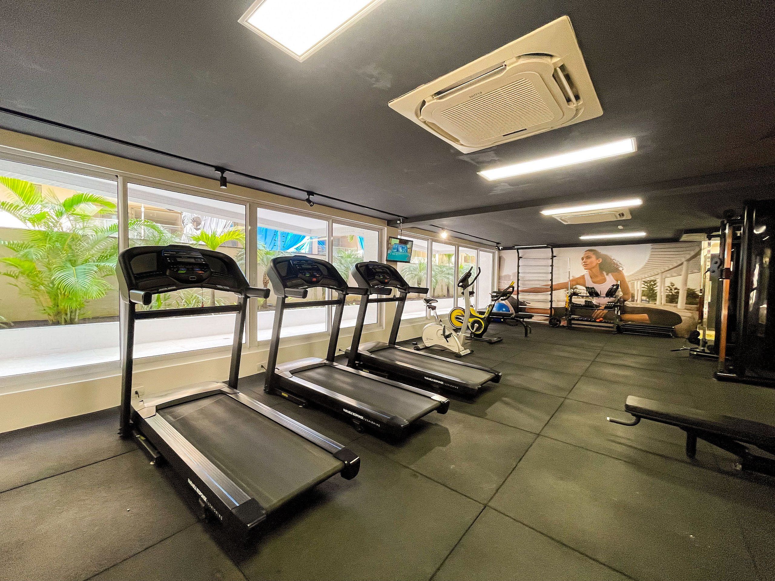 Uma academia com esteiras, bicicletas ergométricas e aparelhos de musculação.