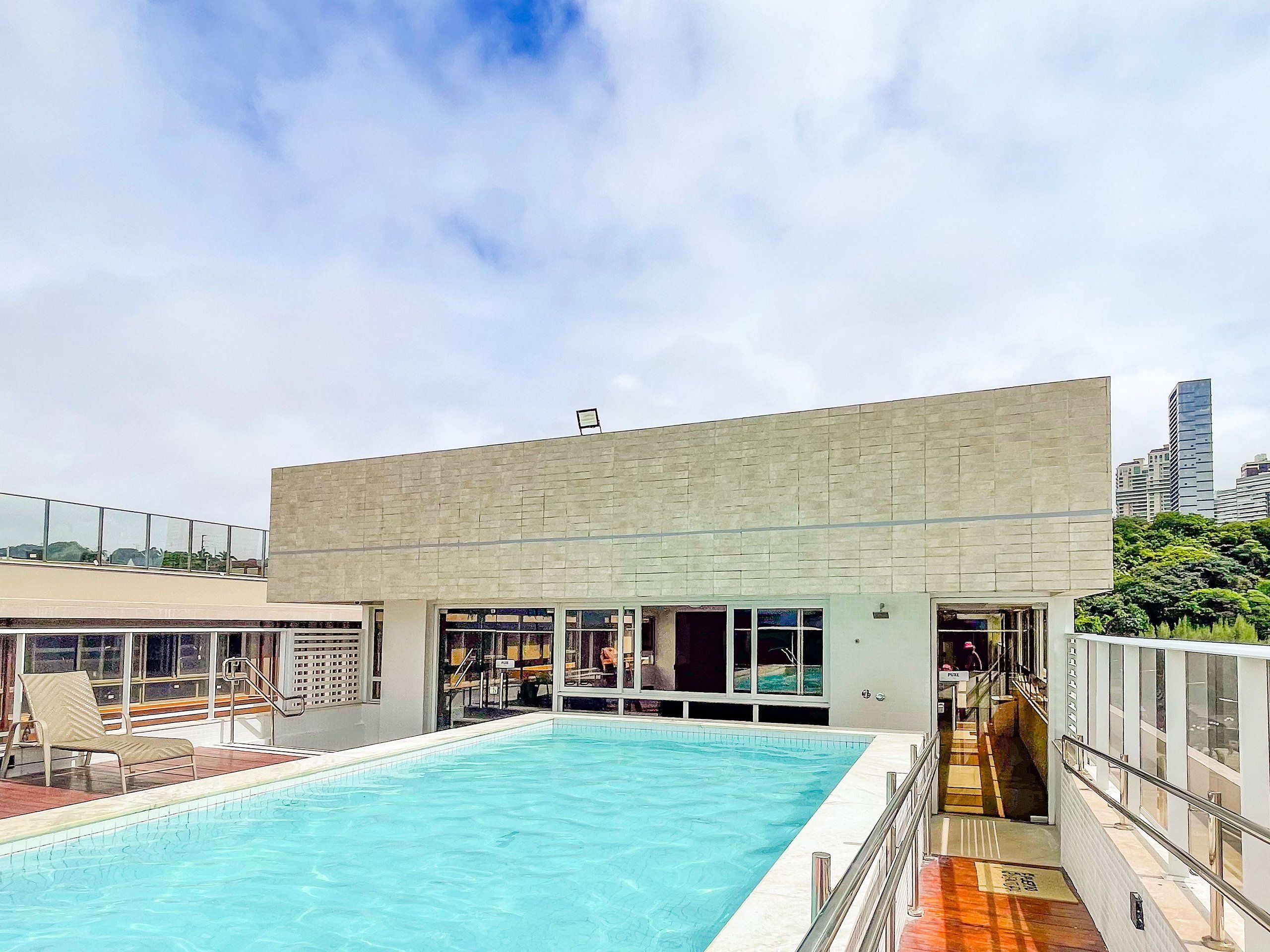 A rooftop swimming pool with a modern building in the background.