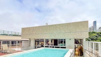 A rooftop swimming pool with a modern building in the background.