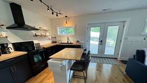 A modern kitchen with a central island, black cabinetry, and a built-in oven. - Mountain Peace 25 Min from Downtown Asheville (Barnardsville)