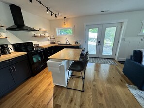 A modern kitchen with a central island, black cabinetry, and a built-in oven. - Mountain Peace 25 Min from Downtown Asheville (Barnardsville)