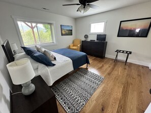 A bedroom with a bed, bedside table, lamp, dresser, chair, and artwork on the walls. - Mountain Peace 25 Min from Downtown Asheville (Barnardsville)