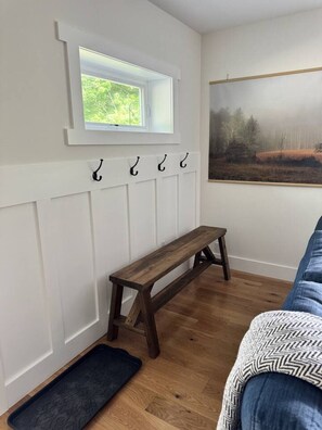 A room with a wooden bench, a window with a view, a coat rack, and a door with a doormat. - Mountain Peace 25 Min from Downtown Asheville (Barnardsville)