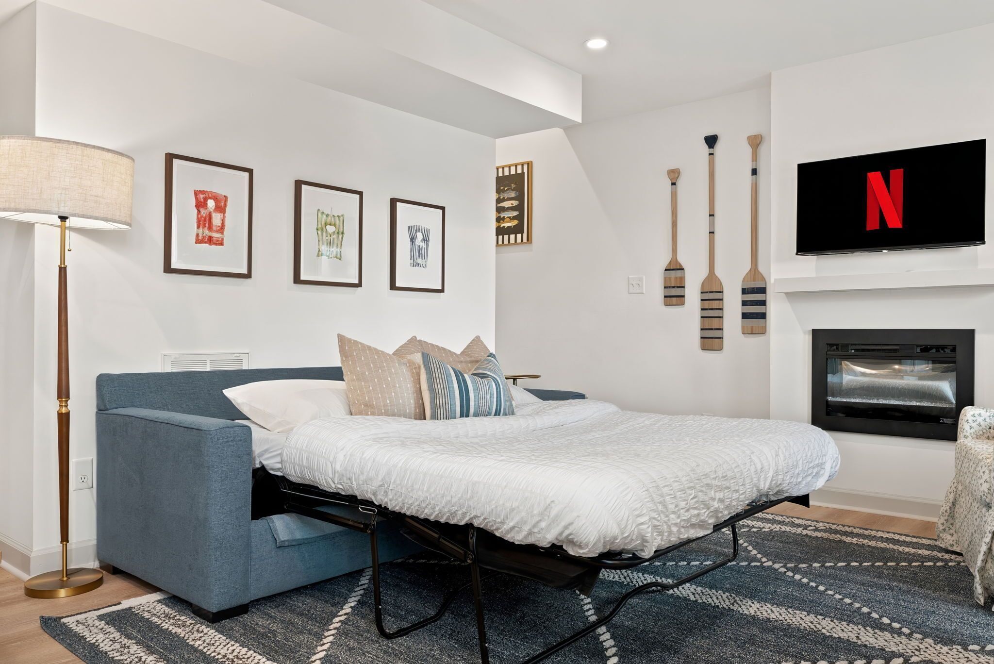 A modern bedroom with a bed, a sofa, a TV, and artwork on the wall.